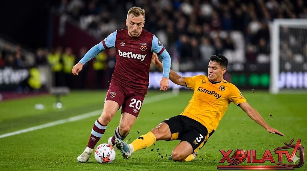 Xoilac TV diem nong tran dau West Ham vs Wolves, hinh anh can canh Jarrod Bowen (West Ham, so 20) dốc bóng va cắt chéo vao khu vực half-space, cơ bắp căng thẳng và mồ hôi rơi, đang đối đầu trực tiếp voi Santiago Bueno (Wolves, so 3) đang xoạc bóng va truy cản quyết liệt. Cả hai cầu thủ thể hiện sự quyết tâm tột độ, biểu cảm gương mặt căng thẳng